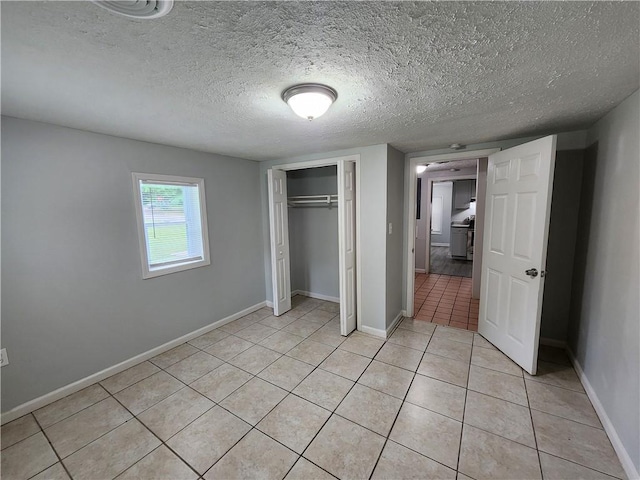 908 Davis St, Monroe, GA 30655 - unfurnished bedroom with light tile patterned floors, a textured ceiling, baseboards, and a closet