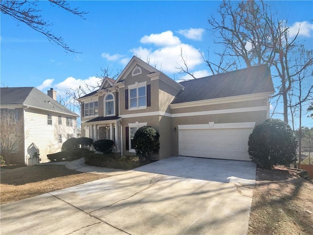 traditional home with driveway, an attached garage, and stucco siding