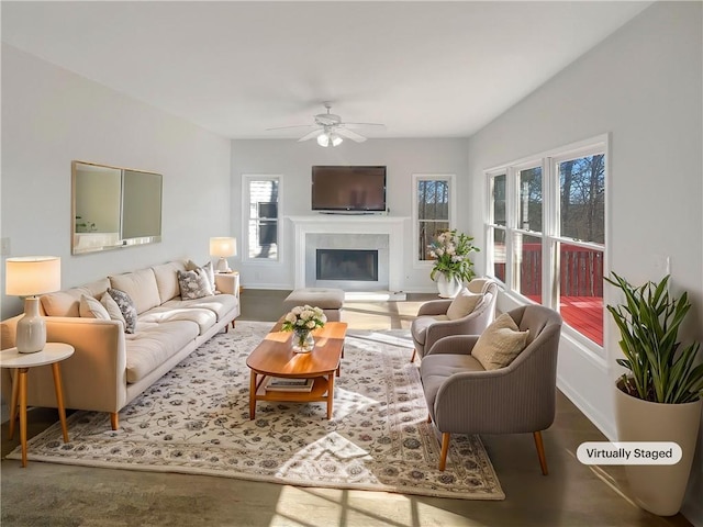 living area featuring a glass covered fireplace and ceiling fan