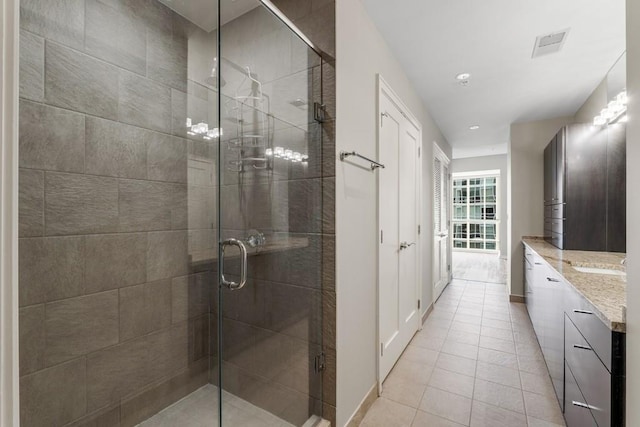 bathroom with tile patterned floors, a shower with door, and vanity