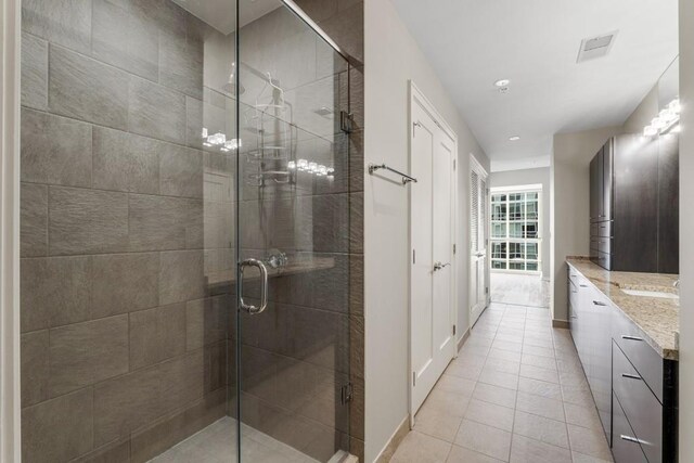 bathroom featuring visible vents, baseboards, tile patterned floors, vanity, and a stall shower