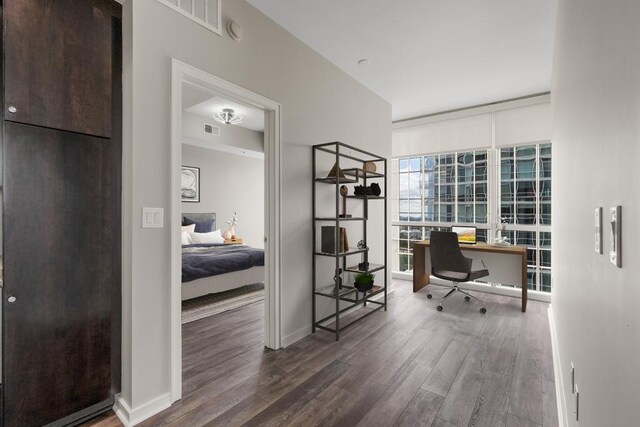 home office with expansive windows, visible vents, wood finished floors, and baseboards
