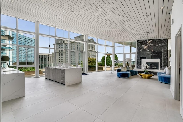 unfurnished sunroom featuring a premium fireplace, wooden ceiling, and a healthy amount of sunlight