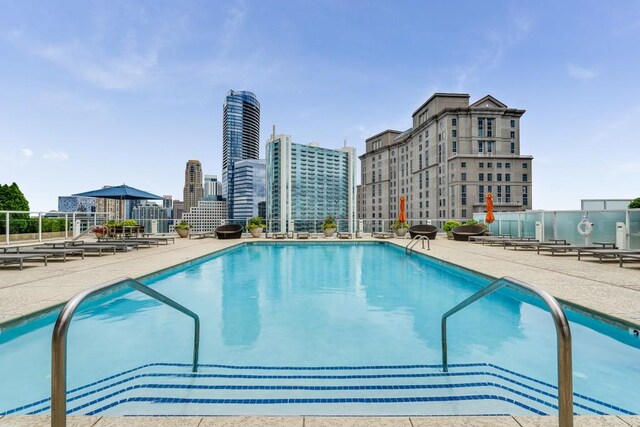pool featuring a city view, fence, and a patio