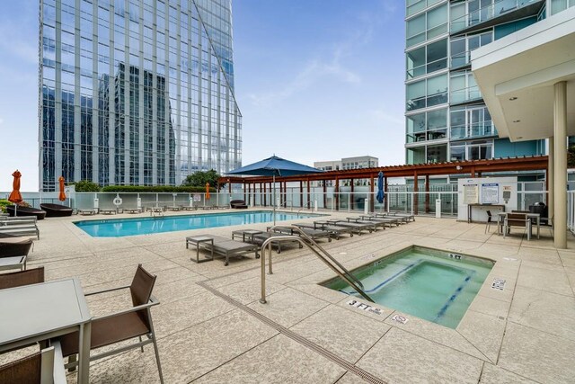community pool with fence, a hot tub, and a patio