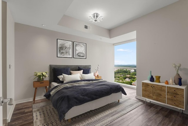 bedroom with baseboards, visible vents, and wood finished floors