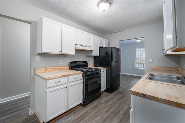 kitchen featuring white cabinetry, sink, black appliances, and butcher block countertops