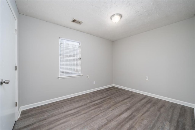 empty room with dark hardwood / wood-style floors and a textured ceiling