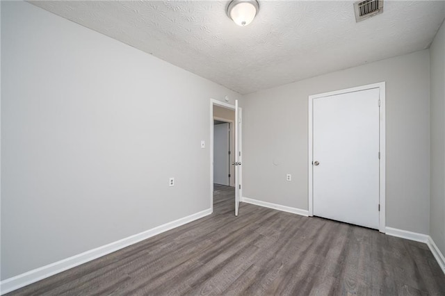 empty room with dark hardwood / wood-style floors and a textured ceiling