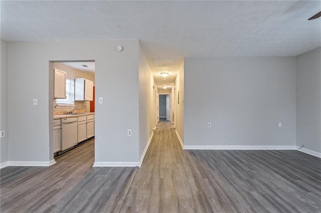 unfurnished room with sink, a textured ceiling, and light hardwood / wood-style floors