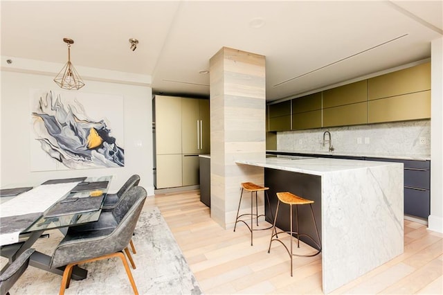 1280 W Peachtree St NW Unit 4003, Atlanta, GA 30309 - kitchen featuring modern cabinets, tasteful backsplash, a breakfast bar, light wood-style flooring, and light stone counters