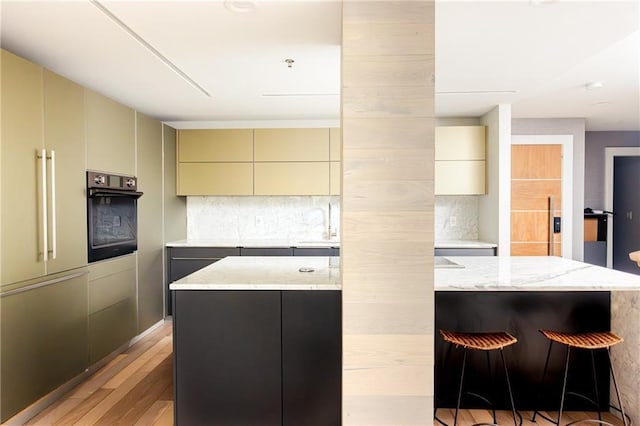 1280 W Peachtree St NW Unit 4003, Atlanta, GA 30309 - kitchen featuring black oven, a kitchen island, cream cabinetry, and light wood-style floors