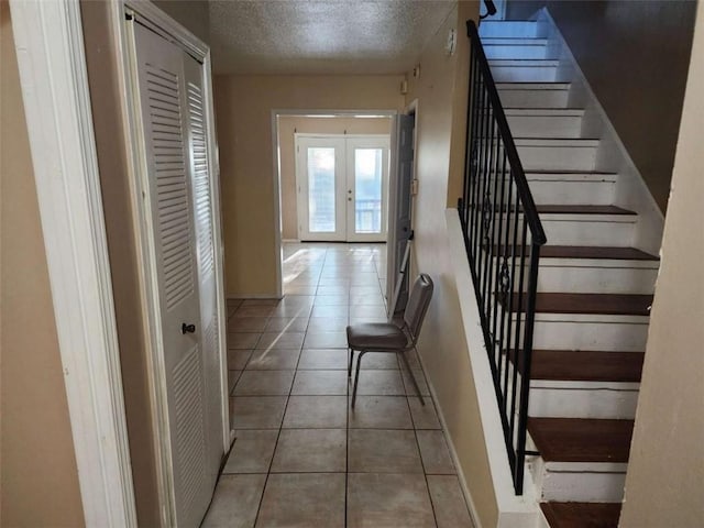 interior space with french doors, a textured ceiling, and light tile patterned floors