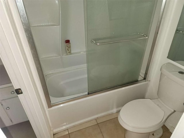 bathroom featuring tile patterned flooring, shower / bath combination with glass door, and toilet