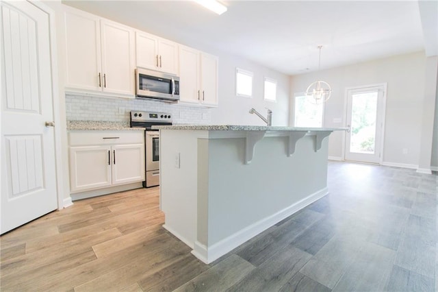 409 Glenn Trl, Winder, GA 30680 - kitchen featuring appliances with stainless steel finishes, a chandelier, light wood-style flooring, and white cabinets