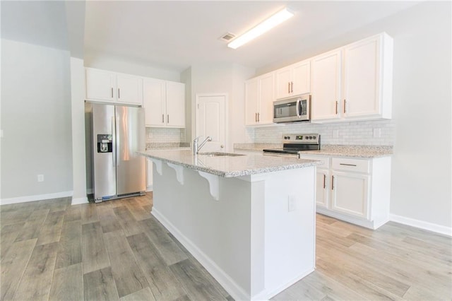 409 Glenn Trl, Winder, GA 30680 - kitchen featuring stainless steel appliances, a center island with sink, white cabinetry, and decorative backsplash