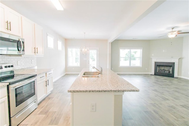 409 Glenn Trl, Winder, GA 30680 - kitchen featuring appliances with stainless steel finishes, light wood-style floors, healthy amount of natural light, and an island with sink