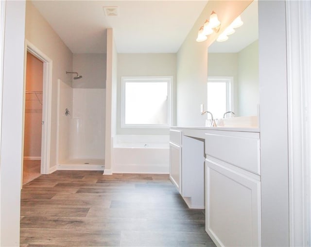 409 Glenn Trl, Winder, GA 30680 - full bath with a walk in shower, a bath, vanity, wood finished floors, and a walk in closet