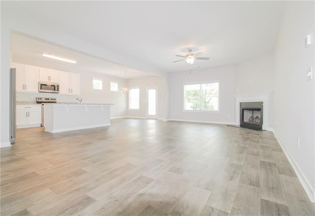 409 Glenn Trl, Winder, GA 30680 - unfurnished living room featuring ceiling fan, a fireplace, light wood-type flooring, and a chandelier