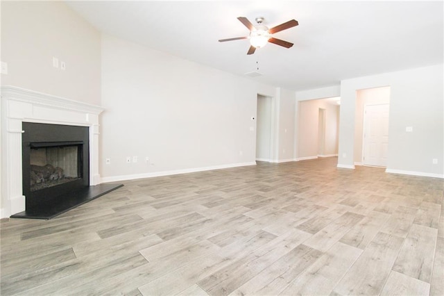 409 Glenn Trl, Winder, GA 30680 - unfurnished living room with a ceiling fan, light wood finished floors, and a fireplace with raised hearth