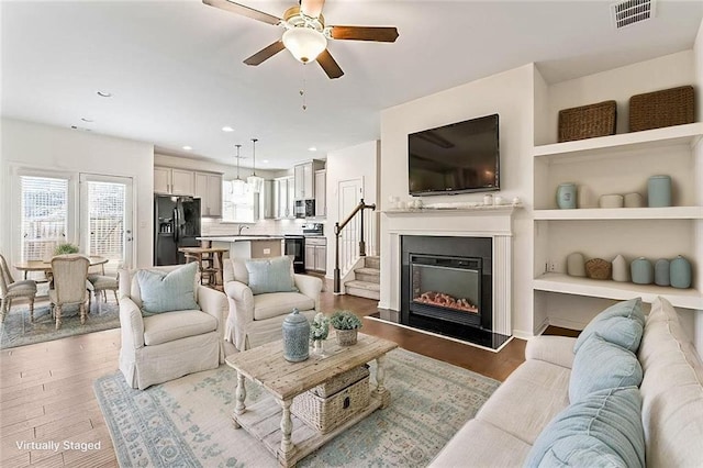 2309 Rolling Trl, Lithonia, GA 30058 - living area featuring wood finished floors, ceiling fan, recessed lighting, a glass covered fireplace, and built in shelves