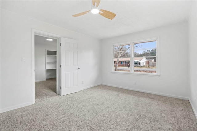 unfurnished bedroom featuring ceiling fan, a walk in closet, and light carpet