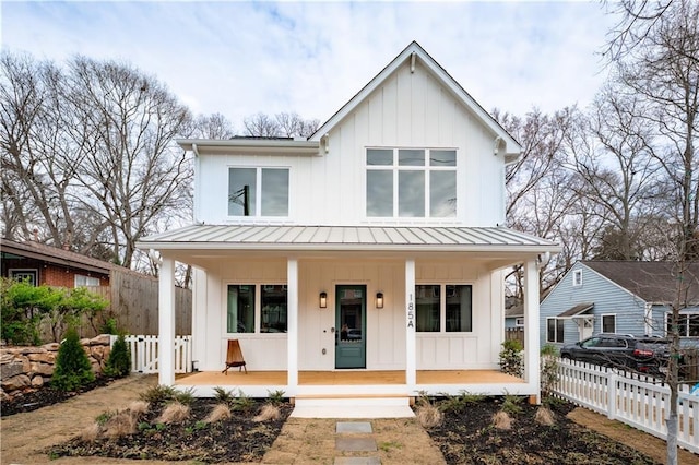 modern farmhouse style home featuring a porch, board and batten siding, a standing seam roof, and fence