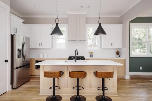 kitchen featuring a kitchen breakfast bar, sink, white cabinetry, stainless steel fridge with ice dispenser, and a center island with sink