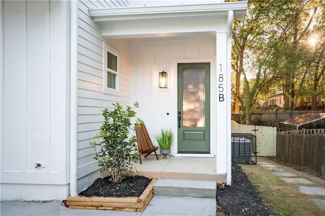 entrance to property featuring board and batten siding and fence