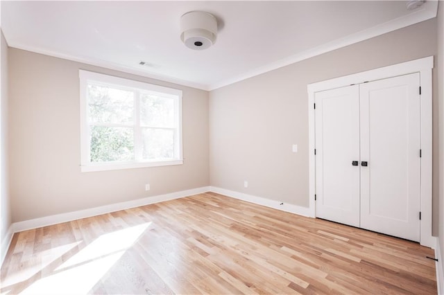 unfurnished bedroom featuring crown molding, light hardwood / wood-style flooring, and a closet