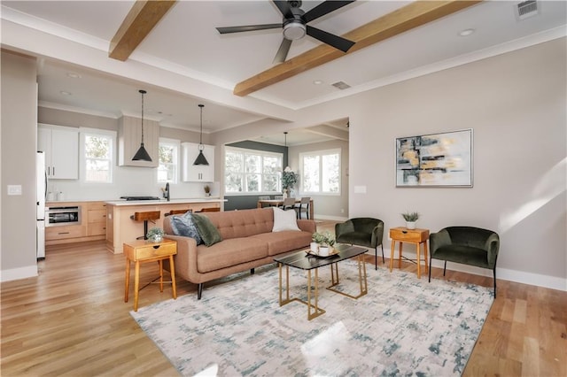 living room with light hardwood / wood-style floors, beamed ceiling, ceiling fan, and ornamental molding