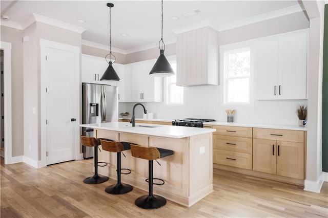 kitchen with range, white cabinetry, stainless steel refrigerator with ice dispenser, sink, and a center island with sink