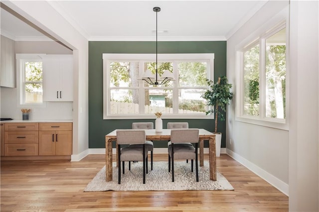 dining room with crown molding, a chandelier, and light hardwood / wood-style flooring