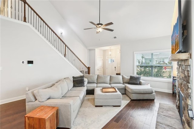 living area with stairway, baseboards, high vaulted ceiling, and wood finished floors