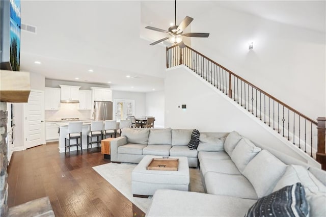 living area with visible vents, dark wood finished floors, a high ceiling, recessed lighting, and stairs