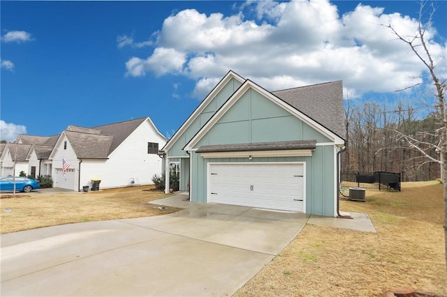 exterior space featuring a yard, board and batten siding, concrete driveway, a shingled roof, and central AC unit