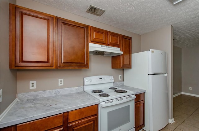 kitchen with light tile patterned floors, white appliances, visible vents, under cabinet range hood, and light countertops