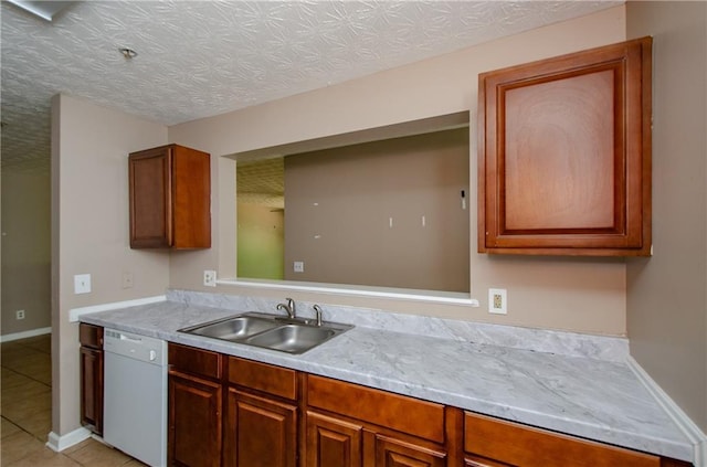 kitchen with light tile patterned floors, dishwasher, light countertops, a sink, and baseboards