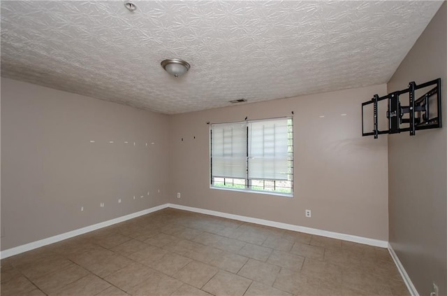 spare room with visible vents, baseboards, tile patterned flooring, and a textured ceiling
