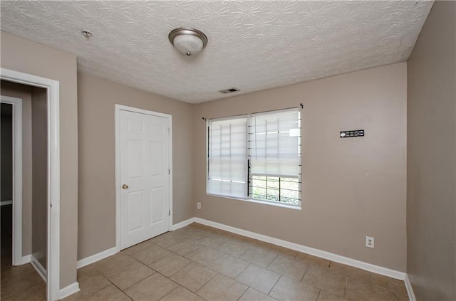 unfurnished bedroom featuring light tile patterned flooring, baseboards, and visible vents