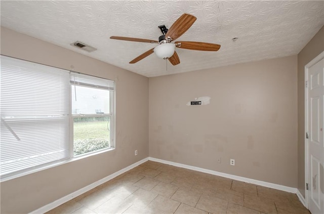 empty room featuring ceiling fan, baseboards, visible vents, and light tile patterned floors
