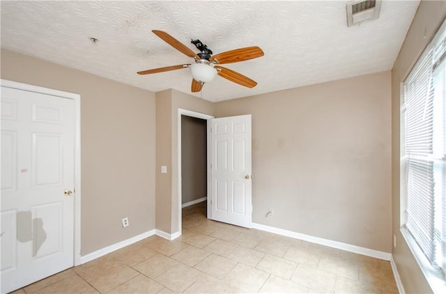 unfurnished bedroom featuring ceiling fan, light tile patterned floors, baseboards, and visible vents
