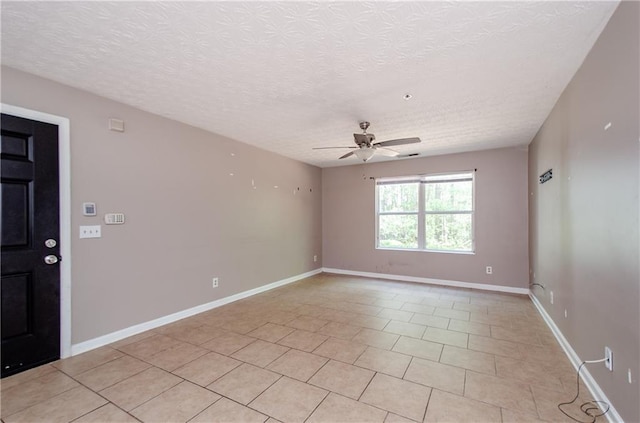 empty room with baseboards, a textured ceiling, a ceiling fan, and light tile patterned flooring