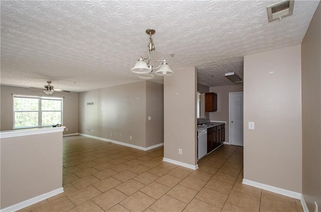 unfurnished room with visible vents, ceiling fan with notable chandelier, baseboards, and light tile patterned flooring