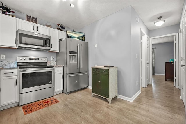 30 Creek Bottom Dr, Covington, GA 30014 - kitchen with appliances with stainless steel finishes, light wood-style floors, white cabinets, a textured ceiling, and light stone countertops