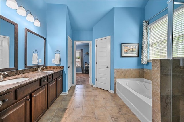 bathroom featuring a sink, a bath, double vanity, and baseboards