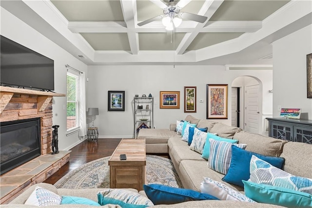 living room with arched walkways, a ceiling fan, a stone fireplace, hardwood / wood-style floors, and coffered ceiling