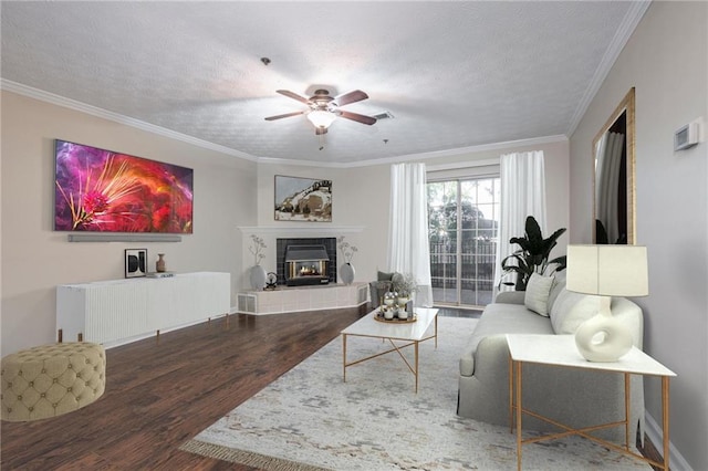 living room with crown molding, a tiled fireplace, dark hardwood / wood-style floors, and a textured ceiling