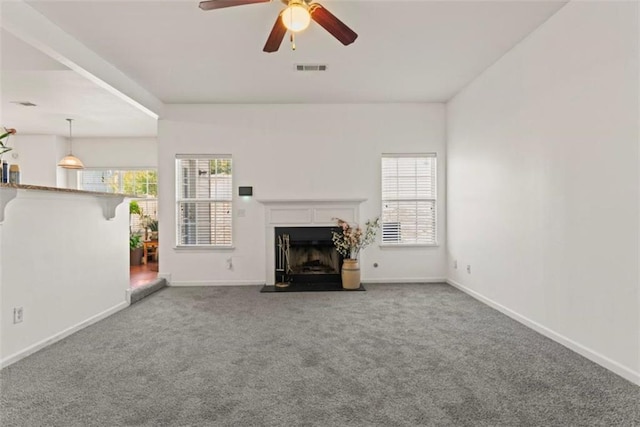 unfurnished living room featuring a fireplace with flush hearth, plenty of natural light, carpet flooring, and a ceiling fan
