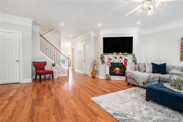 living room with wood-type flooring, ceiling fan, and ornamental molding